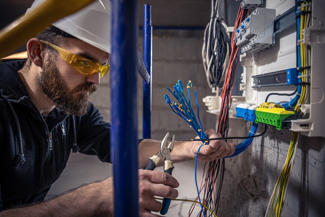 male-electrician-works-switchboard-with-electrical-connecting-cable_169016-15090